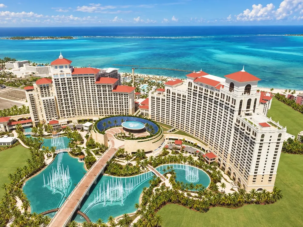 Seen from above, the red roofed Baha Mar resort towers with fountains and pools behind a turquoise sea and a long beach